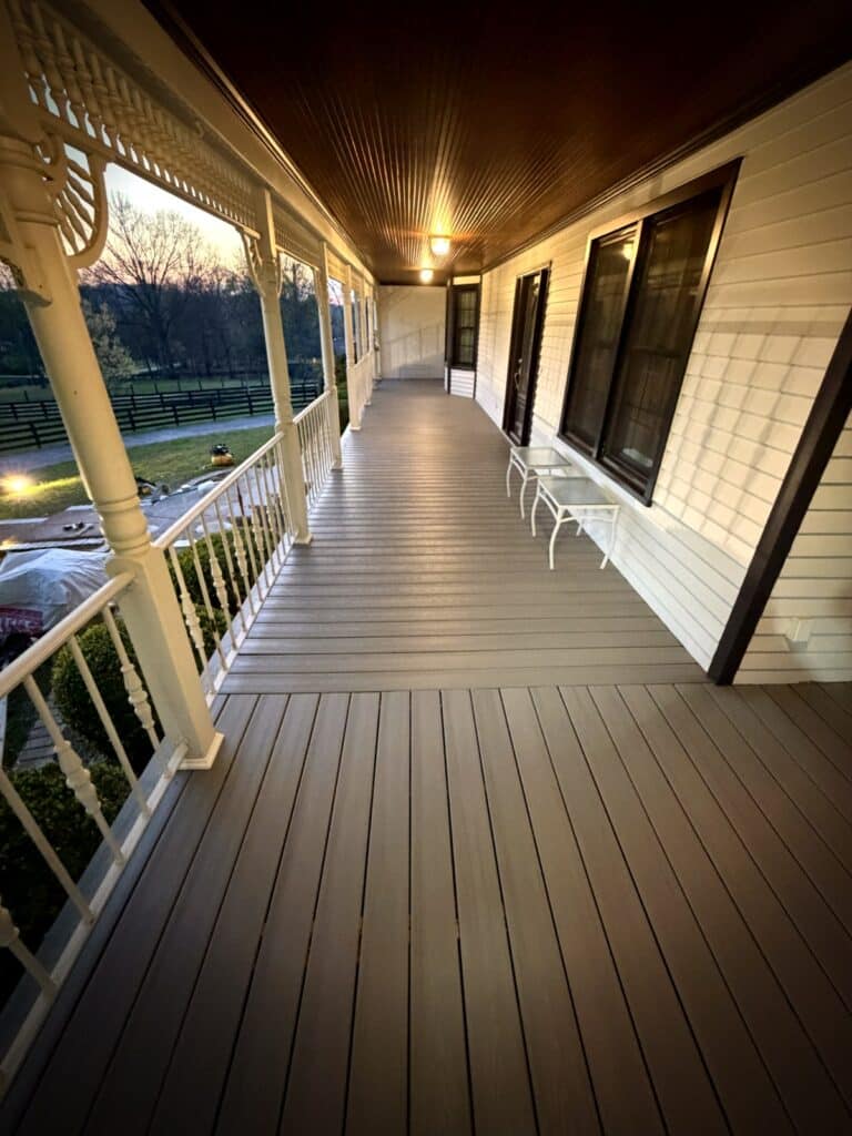 New composite decking on covered wraparound porch at dusk Proper Deck and Fence Middle Tennessee
