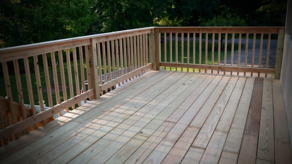 Freshly built pressure-treated wood deck with spindle railing overlooking green yard in Middle Tennessee